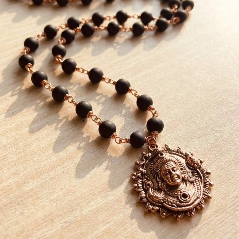 Karungali Malai (Copper Wire) with Lord Murugan Face Pendant on a wooden surface